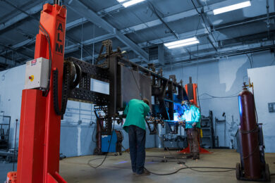 Two men welding, using a positioner